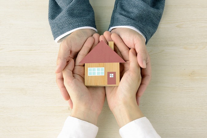 住宅模型を持つ2つの手